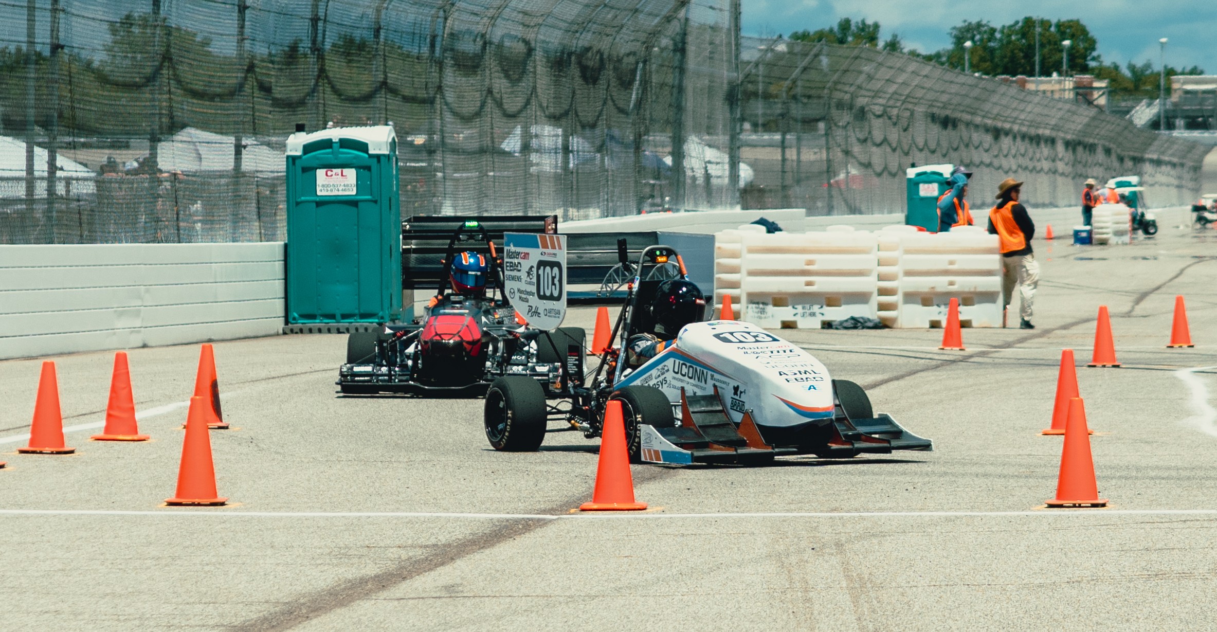UConn Formula SAE team with both cars and team logo